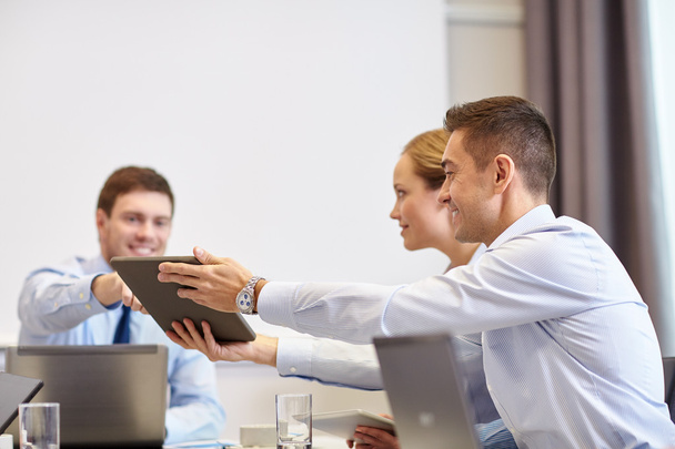 улыбающиеся деловые люди с планшетным ПК в офисе
 - Фото, изображение