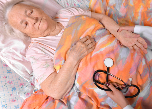 Vrouwelijke conciërge puls van oude vrouw controleren - Foto, afbeelding