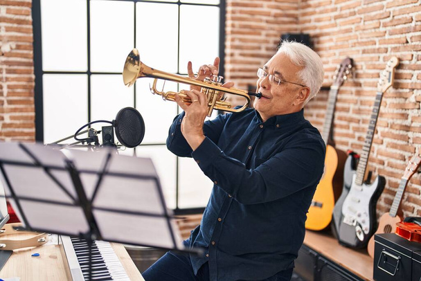 Senior man muzikant die trompet speelt in de muziekstudio - Foto, afbeelding