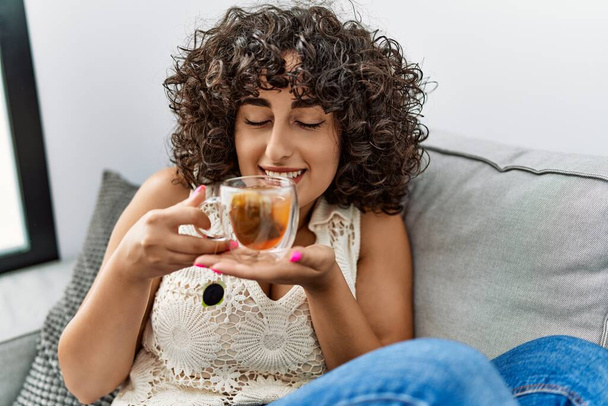 Young middle east woman smiling confident drinking tea at home - Фото, изображение