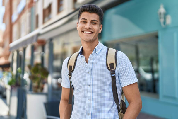 Mladý hispánec muž student usměvavý sebevědomí stojící na ulici - Fotografie, Obrázek