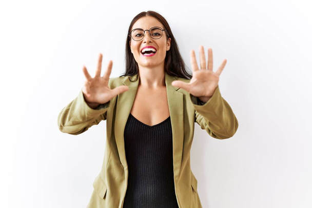 Nuori brunette nainen seisoo yli eristetty tausta osoittaa ylös sormet numero yhdeksän hymyillen luottavainen ja onnellinen.  - Valokuva, kuva
