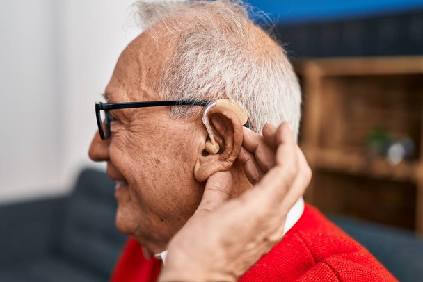 Starší muž usměvavý sebevědomě pomocí hluchoty naslouchátko doma - Fotografie, Obrázek