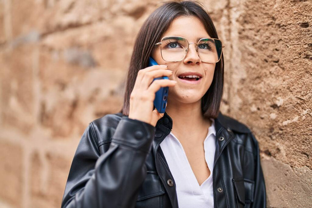 Νεαρή όμορφη ισπανόφωνη γυναίκα χαμογελά αυτοπεποίθηση μιλώντας στο smartphone πάνω από απομονωμένο πέτρινο φόντο - Φωτογραφία, εικόνα