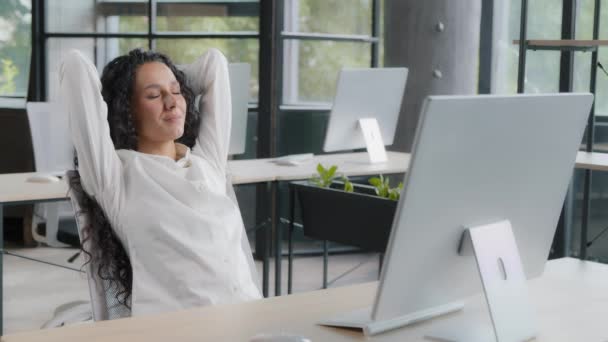 Relaxed woman manager taking break at workplace holding hands behind head resting after completing work sitting at desk dreaming with closed eyes enjoying relaxation feels satisfaction by work done - Imágenes, Vídeo