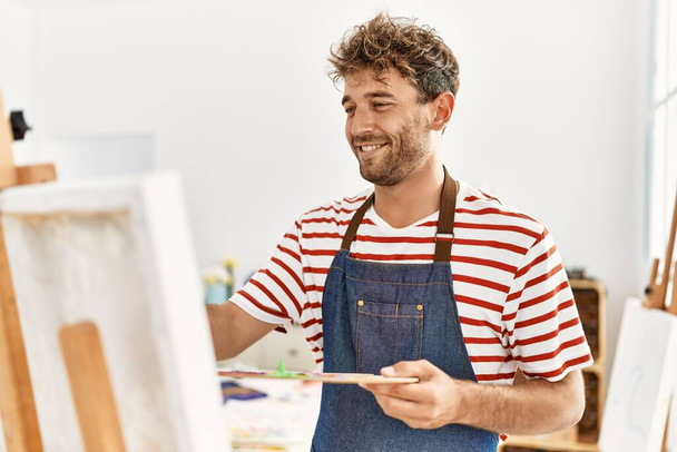 Jeune homme hispanique souriant dessin confiant au studio d'art - Photo, image