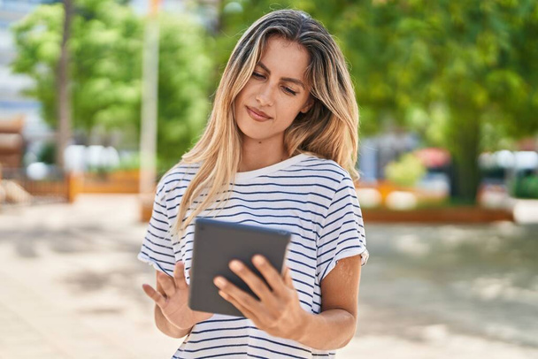 Junge blonde Frau benutzt Touchpad im Park - Foto, Bild