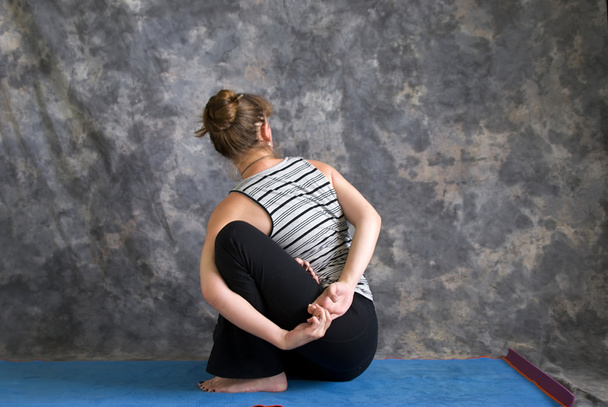 Mulher fazendo postura de Yoga Baddha Ardha Matsyendrasana ou ligado lo
 - Foto, Imagem