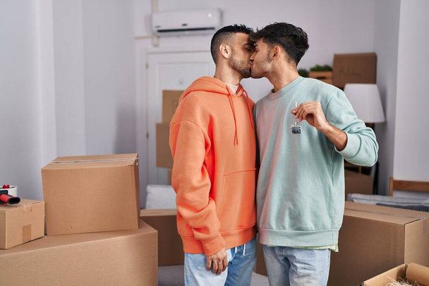 Двое мужчин держат ключ и целуются в новом доме - Фото, изображение