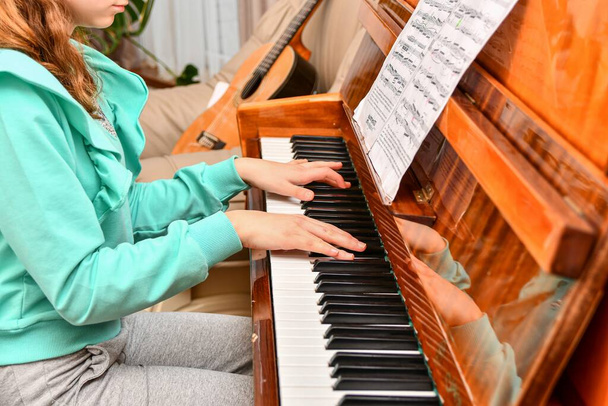 Дівчина грає на піаніно відповідно до нот у музичній школі
. - Фото, зображення