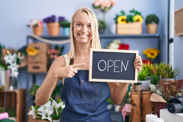 Young caucasian woman working at florist with open sign smiling happy pointing with hand and finger  - Photo, Image