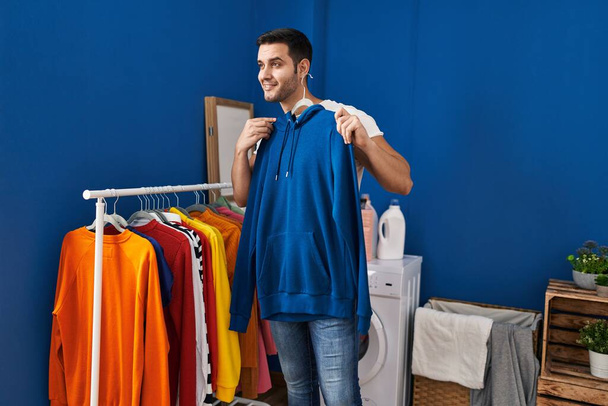 Fiatal spanyol férfi ruhákat öltöztet a mosókonyhában. - Fotó, kép