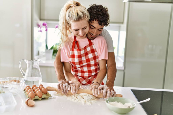 Молодая пара улыбается счастливый месить тесто с руками на кухне. - Фото, изображение