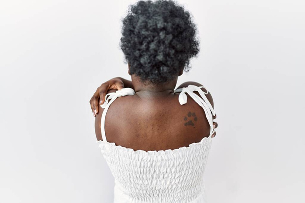 Young african woman standing over white isolated background hugging oneself happy and positive from backwards. self love and self care  - Foto, afbeelding