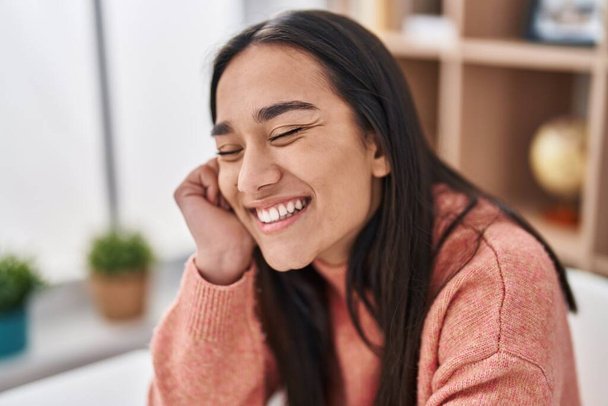 Young hispanic woman smiling confident sitting on table at home - Foto, Bild