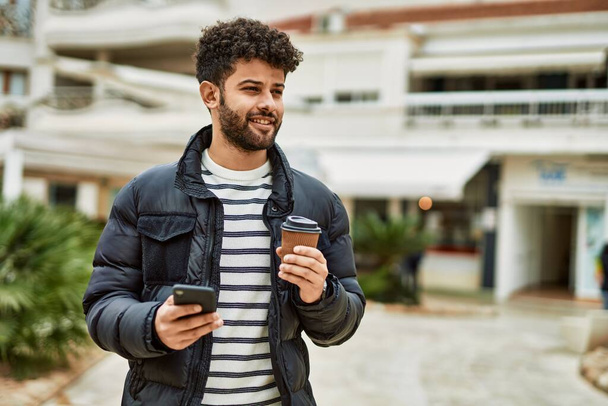 Hombre árabe joven usando teléfono inteligente al aire libre en la ciudad - Foto, imagen
