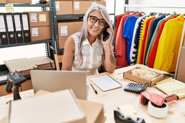 Középkorú ősz hajú nő üzleti e-kereskedelmi dolgozó beszél az okostelefonon az irodában - Fotó, kép