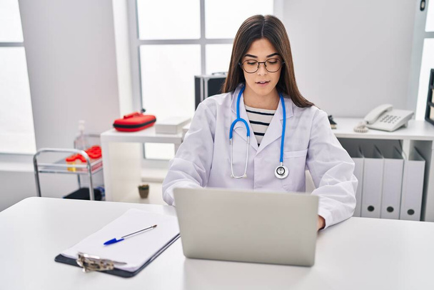 Jeune belle hispanique femme médecin en utilisant un ordinateur portable travaillant à la clinique - Photo, image