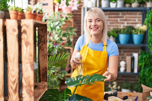 Young blonde woman florist using difusser working at florist - Фото, зображення