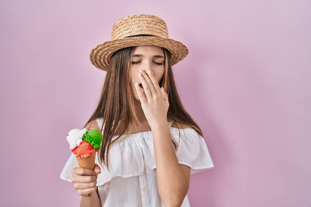 Teenager girl holding ice cream bored yawning tired covering mouth with hand. restless and sleepiness.  - Foto, immagini