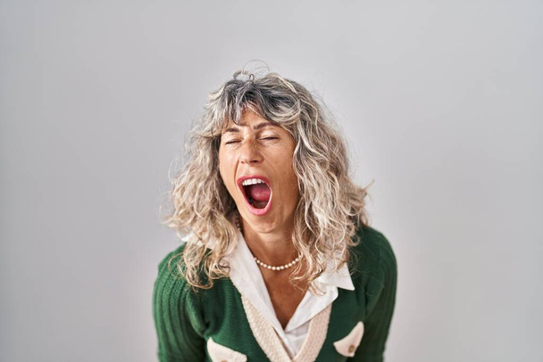 Middle age woman standing over white background angry and mad screaming frustrated and furious, shouting with anger. rage and aggressive concept.  - Photo, Image