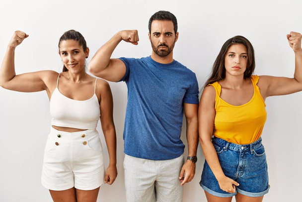 Groep van jonge Latijns-Amerikaanse mensen staan over geïsoleerde achtergrond sterke persoon tonen arm spier, zelfverzekerd en trots op de macht  - Foto, afbeelding