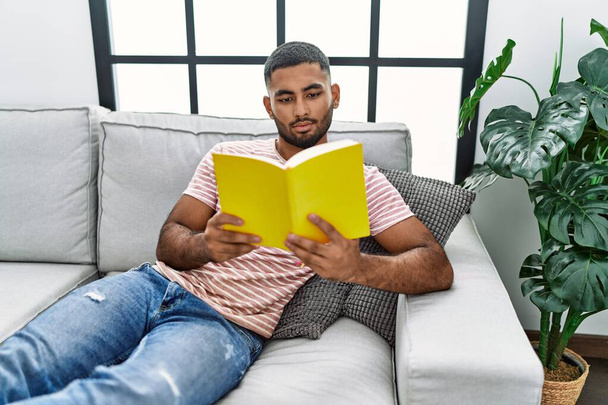 Young arab man reading book at home - Foto, imagen