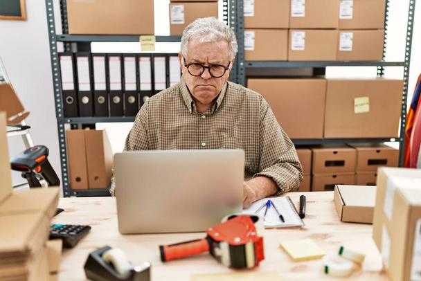 Старший кавказький чоловік, який працює в малого бізнесу в електронній комерції з ноутбуком скептично і нервово, розчаровується через проблеми. негативна людина
.  - Фото, зображення