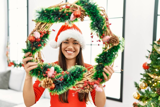 Jeune femme latine souriant confiant tenant décor de Noël à la maison - Photo, image