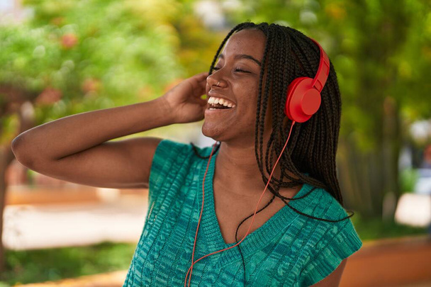 Африканська американка усміхається і впевнено слухає музику в парку. - Фото, зображення
