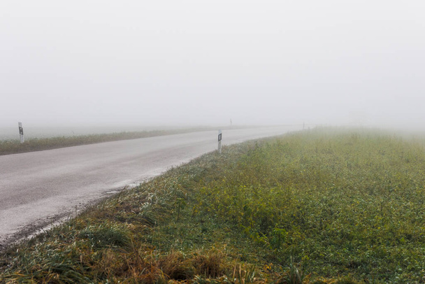 Venkovská silnice v husté mlze s reflektory téměř neviditelných vozidel - Fotografie, Obrázek
