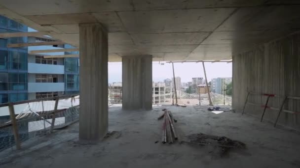 Camera moves around construction site of high building with view of city on sunny day. Apartment building under construction. Developer, real estate investment. concrete monolithic piles. - Footage, Video