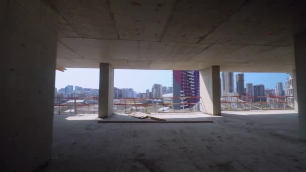 Camera moves around construction site of high building with view of city on sunny day. Apartment building under construction. Developer, real estate investment. concrete monolithic piles. - Video