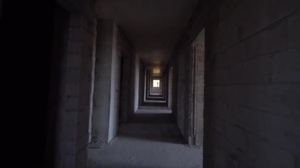 A kamera átmegy az építkezésen a sötét folyosón. Építkezés alatt álló lakóház. Fejlesztő, ingatlanbefektetés. beton monolit halom. - Felvétel, videó