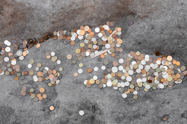 Many coins of different denominations lie on a stone, travelers leave coins to return someday - Zdjęcie, obraz