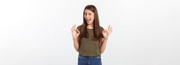 Щаслива молода жінка, показуючи знак з пальцями підморгнута ізольована на сірому фоні
 - Фото, зображення