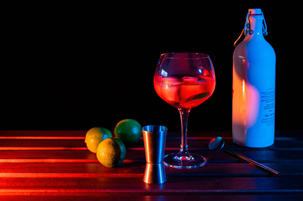 Red cocktail glass with limes and colored lights - Fotó, kép