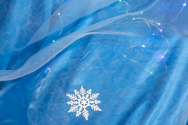 White snowflake cut out from tracing paper on blue background, top view. Handmade new year decoration. - Valokuva, kuva