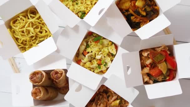Take away food concept. Spring rolls, fried rice with chicken, curry and wok noodles. Healthy lunch. Take and go asian food. Top view flat lay - Filmagem, Vídeo