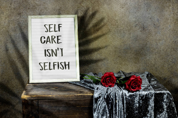 Self Care Isn't Selfish in wooden ornate picture frame photo with red roses flowers on wooden table with textile. vintage photo  - Φωτογραφία, εικόνα