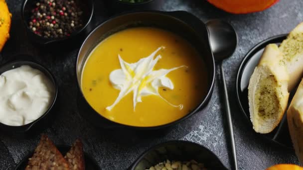 Homemade pumpkin soup with cream and sides. Top view image at stone table. Flat lay - Video