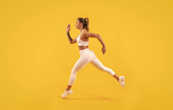 corridore ragazza sportiva in esecuzione su sfondo giallo. - Foto, immagini