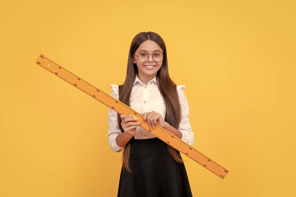 smiling tween girl hold ruler. back to school. algebra and geometry. kid in glassesstudy math. measure the size. trigonometry stationery. measuring and sizing. education for child. mathematics. - Fotografie, Obrázek