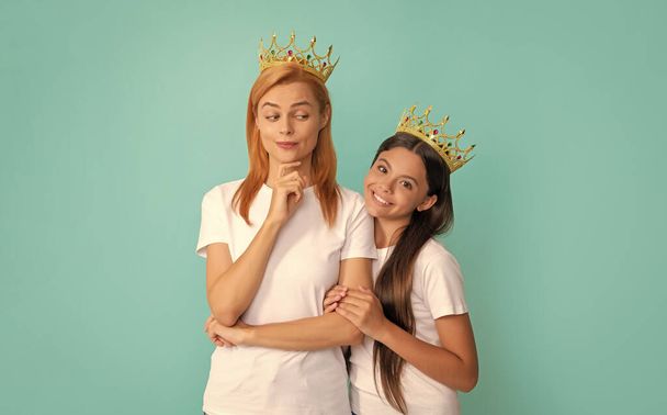I got it from my mother. Selfish mother smile at daughter. Happy woman and girl child in crowns. Mothers day. Mothering and parenting. - Фото, изображение