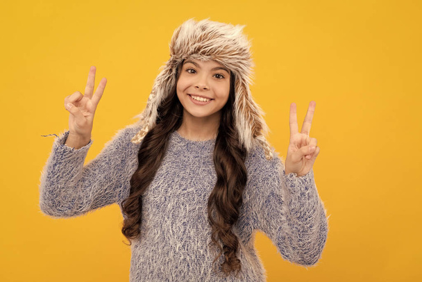 happy kid long hair in hat show peace gesture on yellow background, fashion. - Foto, afbeelding