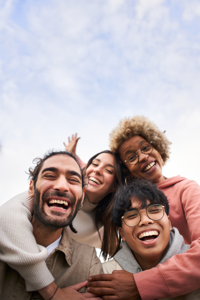 Vertical of a Group of young people looking at the camera outdoors. Happy smiling friends hugging. Concept of community and youth lifestyle. High quality photo - Foto, imagen