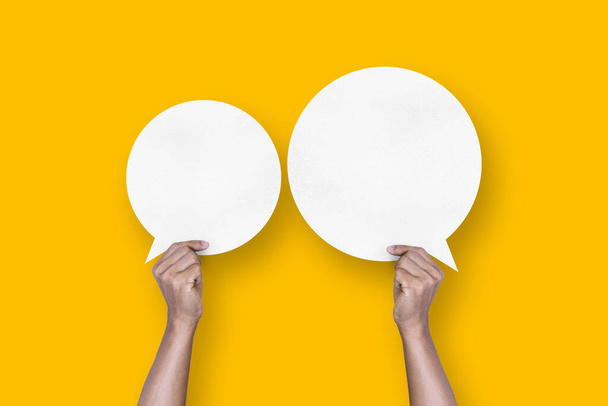 hand holding round white paper balloons speech bubbles isolated on yellow background communication bubbles - Photo, Image