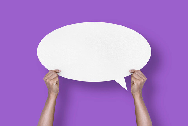 hand holding round white paper balloons speech bubbles isolated on purple background communication bubbles - Foto, imagen