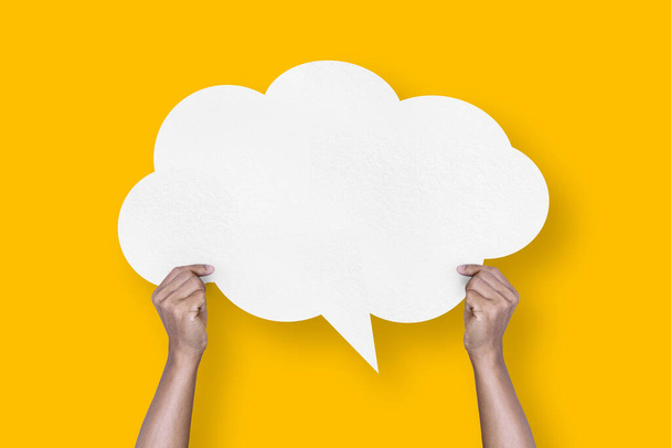 hand holding white paper cloud shape speech bubble balloon isolated on yellow background communication bubbles. - Fotoğraf, Görsel
