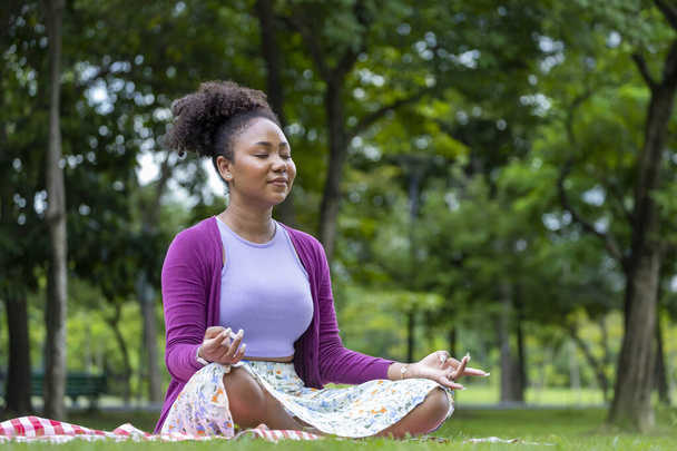 African American woman relaxingly practicing meditation in the forest to attain happiness from inner peace wisdom for healthy mind and soul - Foto, Imagen